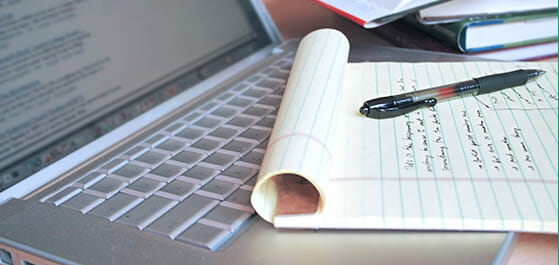 Inhaltsbild: Header: Laptop mit Notizblock, Stift und Büchern, das oberste aufgeschlagenen