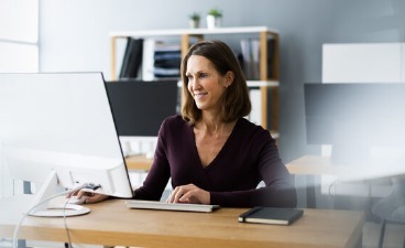 Eine Frau sitzt in ihrem Büro einem PC.