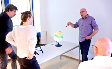 News- Foto: Vier Personen stehen um einen Tisch, auf welchem sich ein Globus befindet