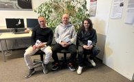 Auf dem Bild sind drei männliche Personen zu sehen. Alle sitzen und halten eine Schultüte in der Hand.