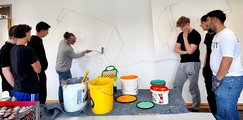Die erste Skizze an der Wand Lehrer malt mit Farbrolle an die Wand während Schüler zusehen.