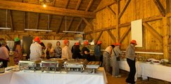 Sommerfest 2026 Mitarbeiter*innen holen sich Essen am Büfett in einem Stadl
