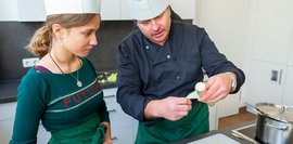 Bildergalerie: Ein Koch erklärt einem Mädchen in einer Küche, wie man Lauch bearbeitet. 
