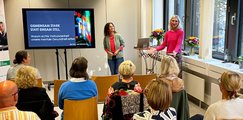 Austausch beim Netzwerkabend Zwei Frauen stehen vorn auf der Bühne neben Bildschirm