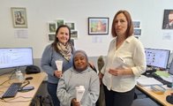 Auf dem Bild sind drei Frauen zu sehen. Eine Frau sitzt, zwei stehen hinter ihr. Alle drei halten eine kleine Schultüte in den Händen.