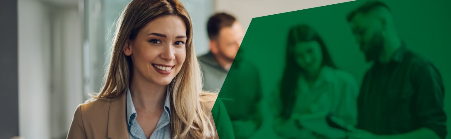 Header: Eine Frau steht mit ihrem Team im Büro.