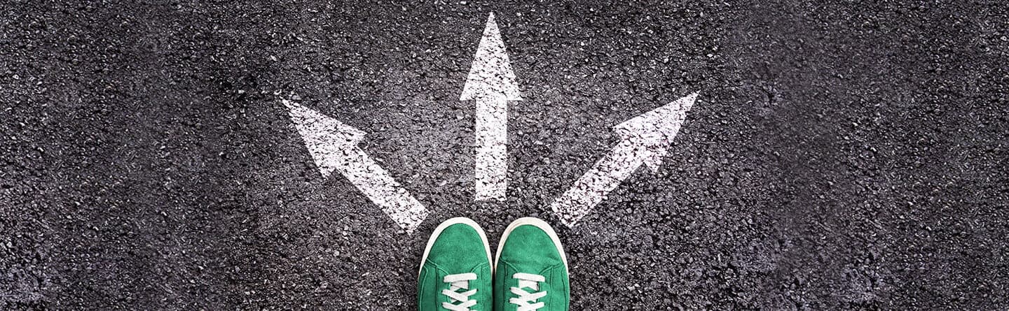 Header: Grüne Schuhe mit 3 in verschiedene Richtungen zeigende Pfeile auf dem Asphaltboden.