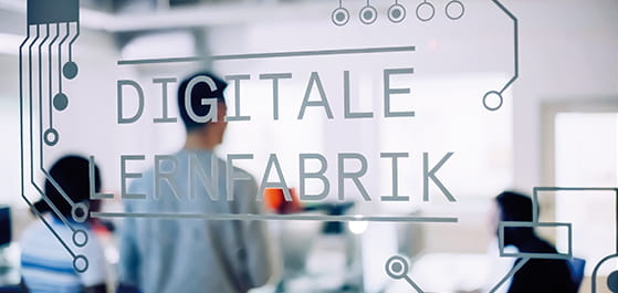 Glastür mit Aufschrift "Digitale Lernfabrik" und Personen
