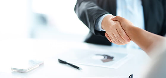 Inhaltsbild: Angeschnittenes Bild von einem Händeschütteln in einem Meeting in einem modernen Büro.