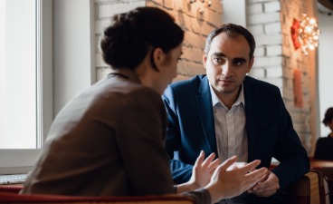 Beratungsgespräch in ruhiger Atmosphäre: Zwei Personen sitzen sich gegenüber und besprechen berufliche Perspektiven.