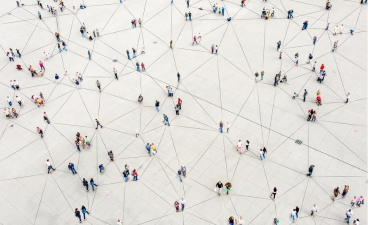 Viele Menschen stehen verstreut auf einer Fläche, verbunden durch Linien – Symbol für Vernetzung und Austausch.