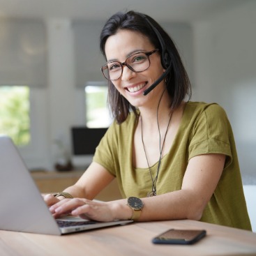Eine Frau mit Headset arbeitet an einem Laptop.