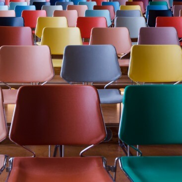 Reihen von bunten Stühlen, nach hinten ansteigend.