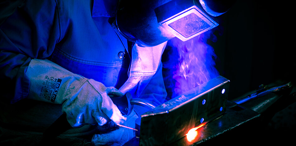 Ein Mann in Schutzausrüstung schweißt ein Metallstück