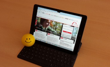 Tablet mit einem Lernprogramm auf einem Tisch und gelber Ball mit Gesicht