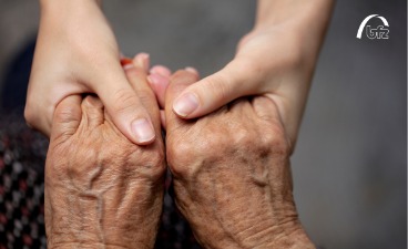 Zwei junge und zwei alte Hände greifen ineinander um sich zu helfen 