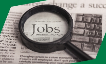Eine Lupe sucht in einer Zeitung nach passenden Jobs 