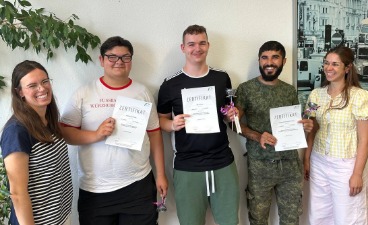Drei Absolventen der WAE mit ihren Abschlusszeugnissen und zwei Mitarbeiterinnen der bfz Augsburg.