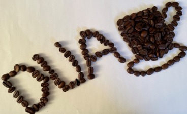 Bild aus Kaffeebohnen mit dem Schriftzug „DUA“ und einer Tasse Kaffee.