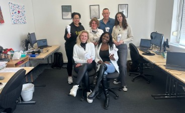 Das Bild zeigt sechs Umschüler/innen im Klassenraum. Alle halten eine kleine Schultüte in der Hand. Zwei Frauen sitzen vorne und hinter ihnen stehen vier Personen. Eine Person ist männlich, die restlichen Personen sind weiblich.