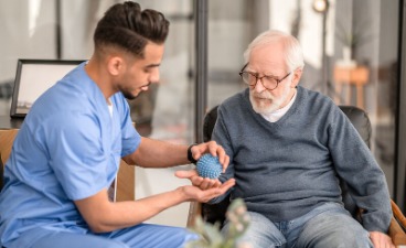 Ein Senior trainiert mit einem Pfleger die Beweglichkeit