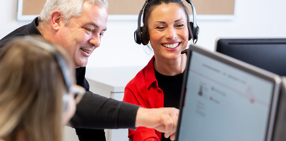 Galeriebild: Mann zeigt einer Frau mit Headset etwas auf einem Bildschirm.