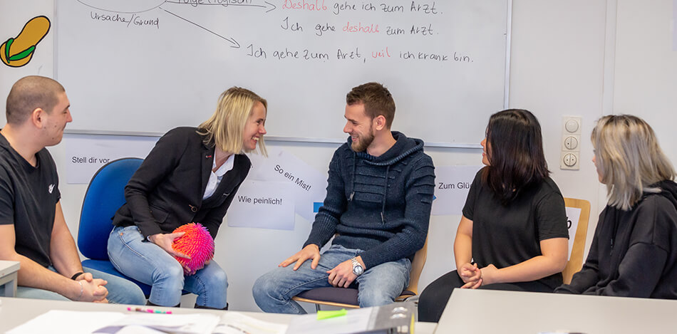 Inhaltsbild: Teilnehmende eines Integrationskurses üben Grammatik-Fragmente auf Zuwurf eines Balls.