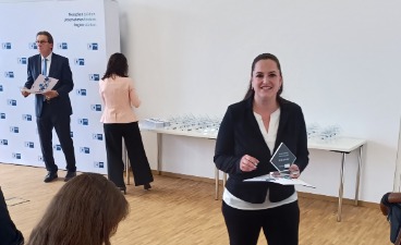 Frau zeigt lächelnd ihre Urkunde für Bestnote 