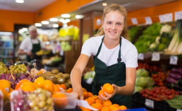 Freundliche Verkäuferin präsentiert Orangen im Supermarkt
