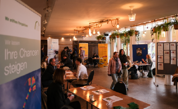 Besucherinnen und Besucher schlendern durch die Jobmesse Eventcoaching in Nürnberg und schauen sich die verschiedenen Stände an.