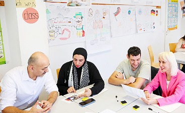 zwei Frau und zwei Männer sitzen im Deutschunterricht an einem Tisch