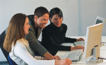 Drei Mitarbeiterinnen schauen auf den Bildschirm.