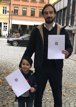 Adnan Ajam Oghli mit Sohn, sie zeigen stolz ihre gerade frisch erworbene Einbürgerungsurkunde