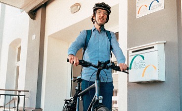 News- Bild: Mann mit Fahrrad posiert vor einem Gebäude