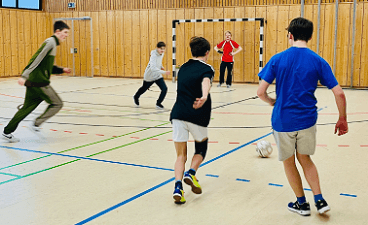 News- Bild: Fünf Fußball spielende Jungen in einer Sporthalle