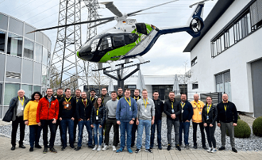 News- Foto: Viele Personen posieren unter einem Helikopter nebeneinander stehend
