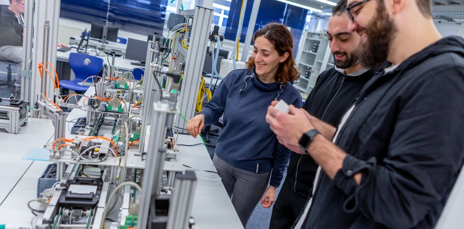 Eine Frau und zwei Männer arbeiten gemeinsam in einer digitalen Lernwerkstatt. 