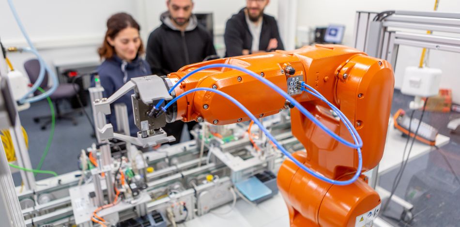 Eine Frau und zwei Männer arbeiten an einer digitalisierten Anlage. 