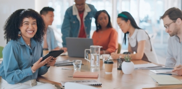 Thumbnail: Eine diverse Gruppe von Menschen unterschiedlicher Herkunft sitzt an einem Tisch und arbeitet beziehungsweise lernt gemeinsam.