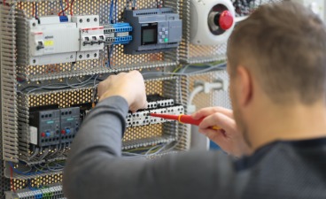 Man sieht einen Elektroniker bei der Arbeit.