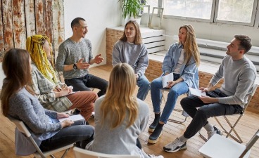 Personen sitzen im Stuhlkreis und unterhalten sich.